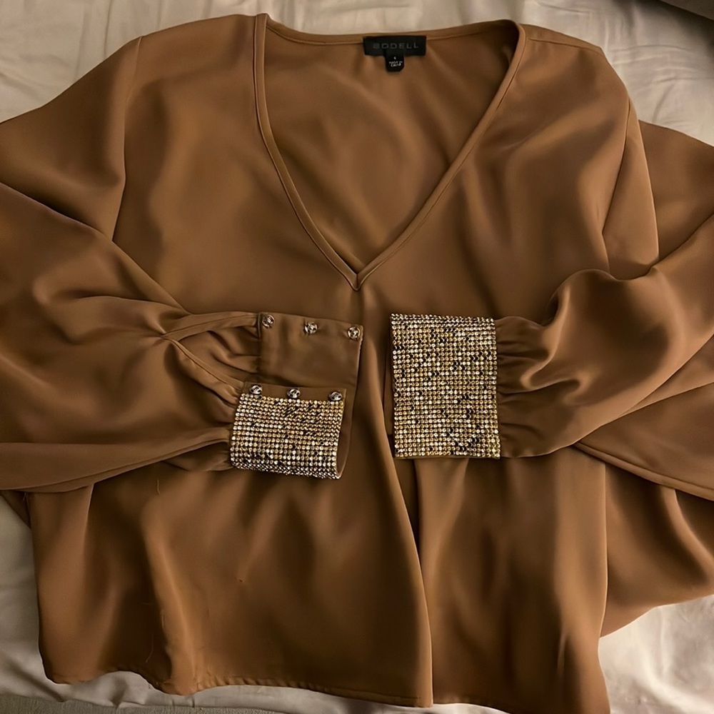 Tan, cropped blouse, with cinched wrist with gold jewels at wrist. Unique cut
